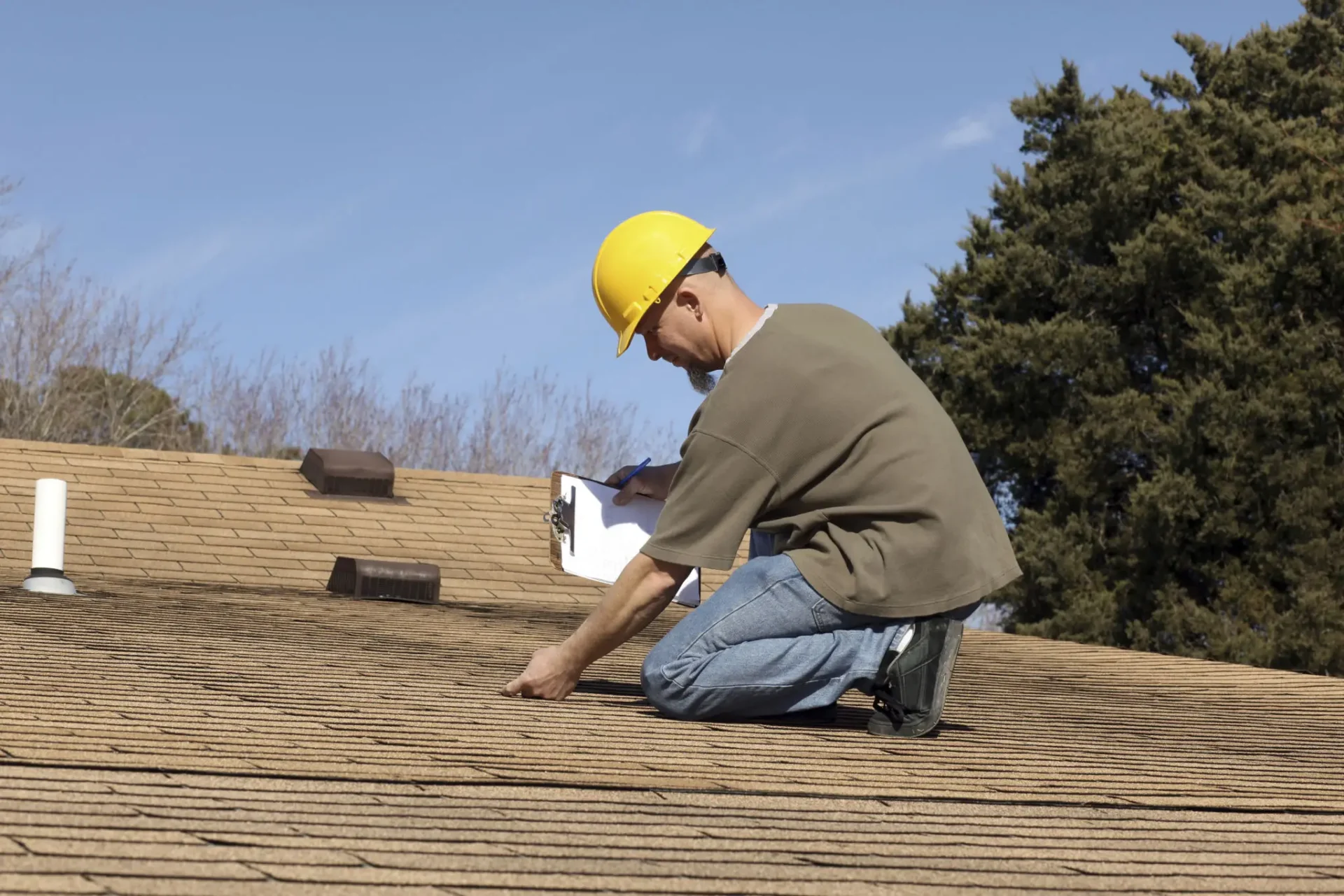 Worker inspecting roof shingles with clipboard