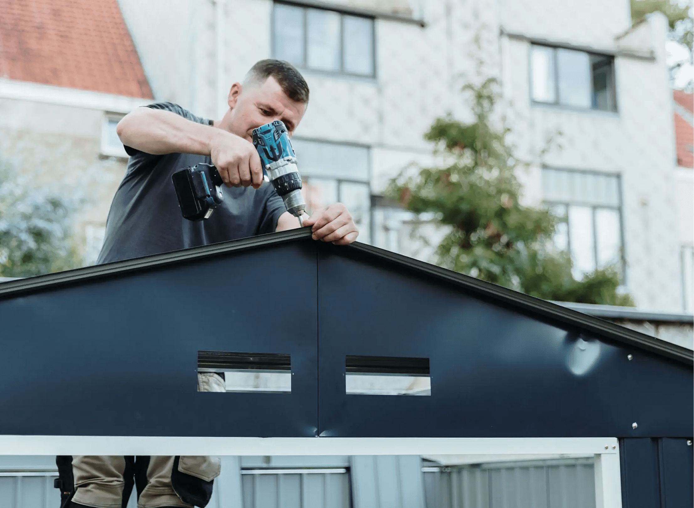 Man using drill on building roof.